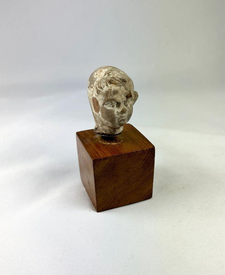 Ancient terracotta boy’s head showing youthful facial features and serene expression.