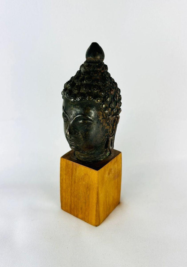 Historical bronze Buddha head on wooden base reflecting meditation iconography