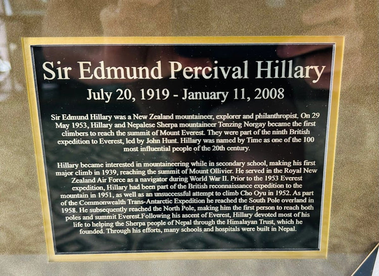 Close-up view of the Sir Edmund Percival Hillary biography plaque, detailing his 1953 Mount Everest ascent with Tenzing Norgay, Antarctic expeditions, and humanitarian work for the Sherpa people. Mounted within a framed display honoring Hillary’s life and legacy.