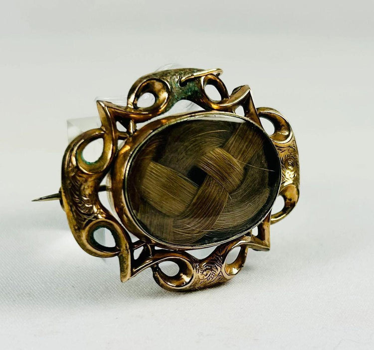Side view of a Victorian mourning hairwork brooch highlighting the domed glass cover.