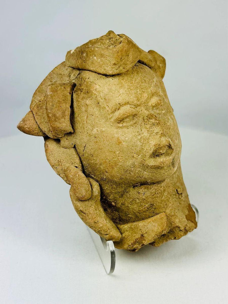 Pre-Columbian figurative terracotta head fragment with headdress, museum-style lighting
