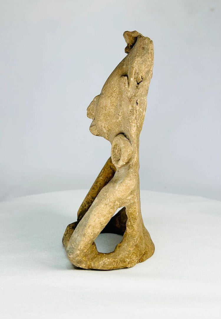 Ancient Mesoamerican ceramic figurine showing a stylized seated human form with rounded facial features and ritual headpiece, likely Zapotec or Olmec influence