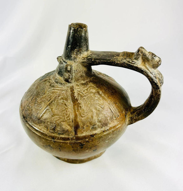 Ancient Peruvian Sicán blackware vessel with sculpted side handle and polished body, Lambayeque Valley region.