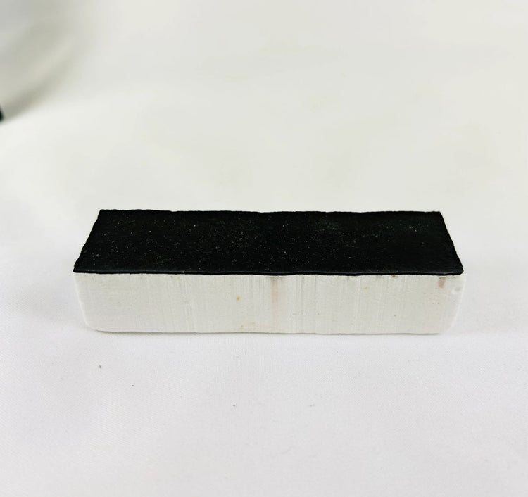 Authentic NASA Space Shuttle Thermal Protection System (TPS) tile from the 1980s, made of silica-based ceramic with black Reaction Cured Glass coating, used for reentry heat resistance, preserved in NASA-issued display case.