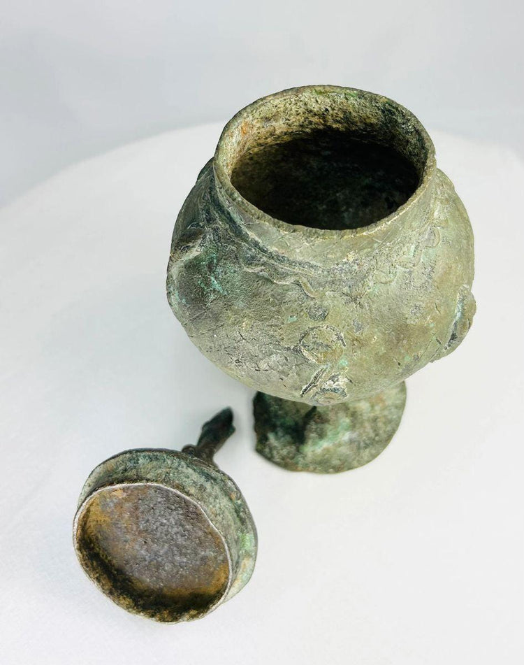 West African Dogon bronze vessel showing sculpted human figure and bulbous ritual form.