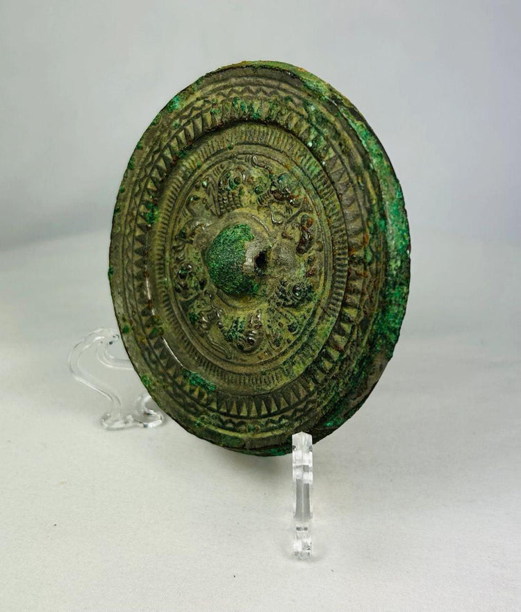Han Dynasty circular bronze mirror with raised central knob and decorative carved motifs.