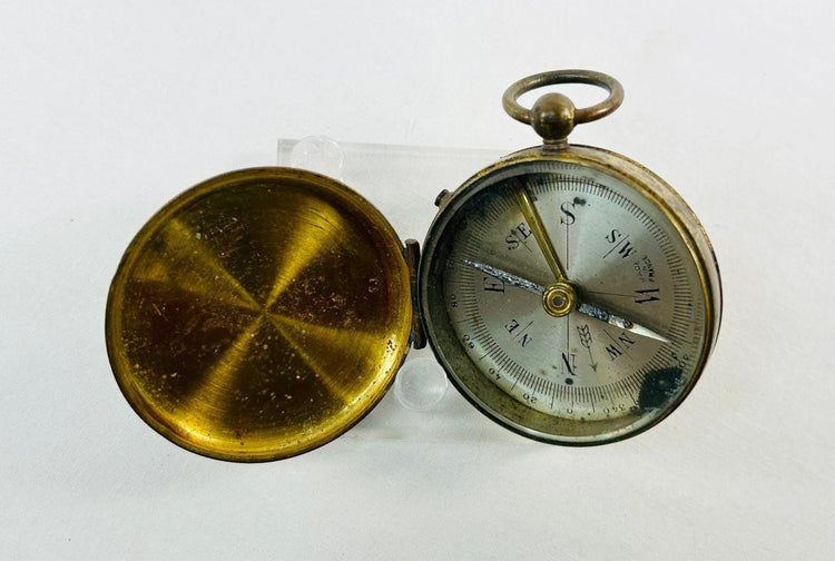 Close-up of the dial on an antique French pocket compass showing cardinal points and 360-degree azimuth scale.