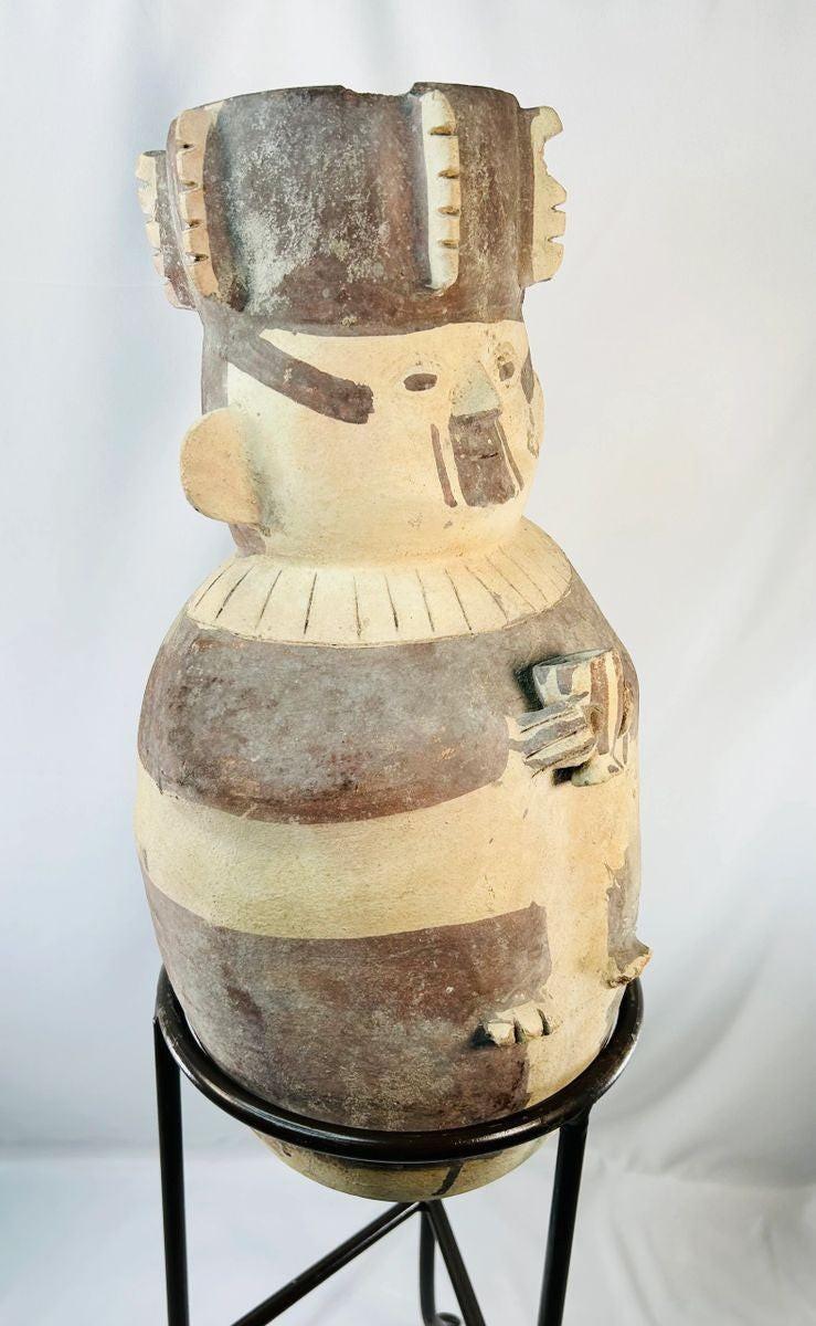 Side view of large Chancay terracotta effigy urn from ancient Peru (1000–1400 CE), Pre-Columbian ceramic vessel with human form, geometric painted bands, and ceremonial headdress, displayed on stand at Relic and Rarity.