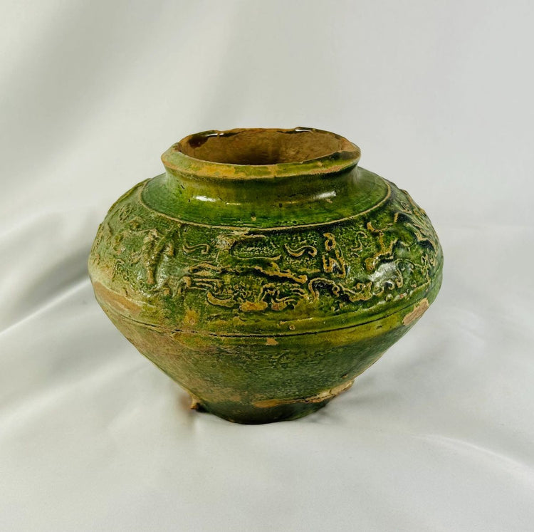 Side view of Han Dynasty green-glazed ceramic vessel with iridescent surface details.