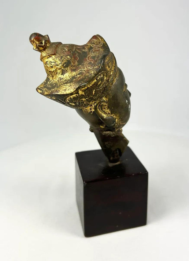 Historic Tibetan bronze Buddha head fragment showing remnants of gilding, stylized facial features, and elaborate crown, representative of Himalayan Buddhist art.