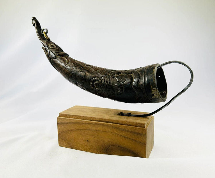 Intricately carved Tibetan Buddhist horn offering tool on stand.