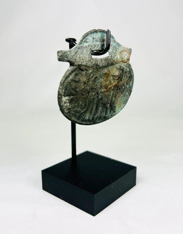 Detailed photograph of Roman bronze pendant featuring military or religious imagery.