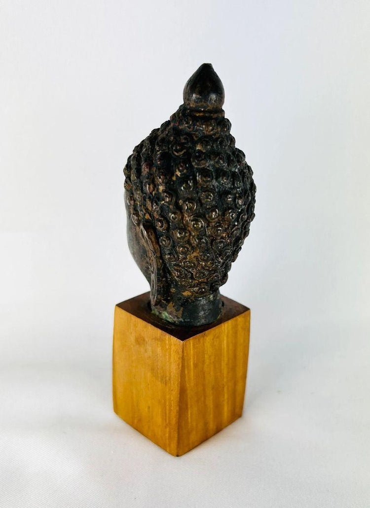 Cast bronze Buddha head with serene expression and ushnisha symbol of wisdom