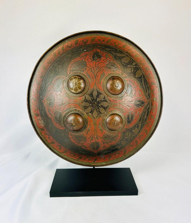 Mughal-era Indo-Persian circular shield with detailed lacquer decoration and central foliate motif.