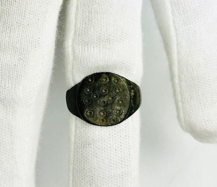 Close-up of a Roman bronze ring showing ring-and-dot solar symbolism on a flat bezel