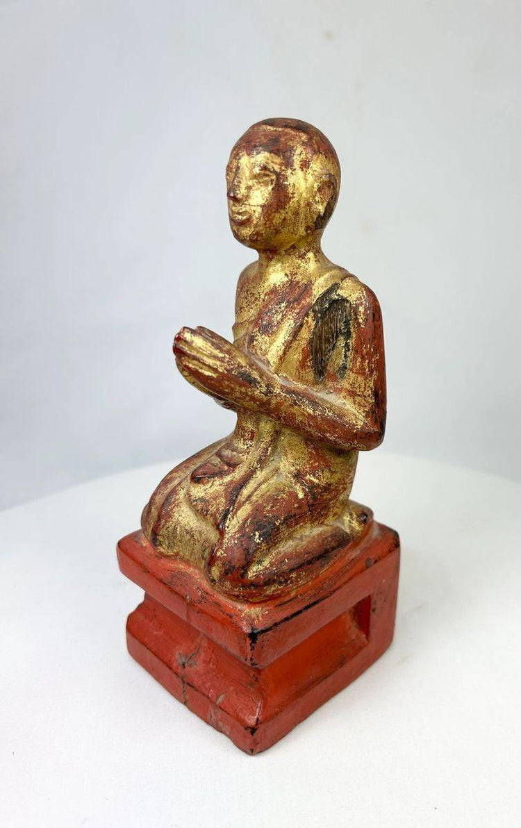 Close-up of the monk’s serene facial expression, highlighting gold leaf remnants and hand-carved details.