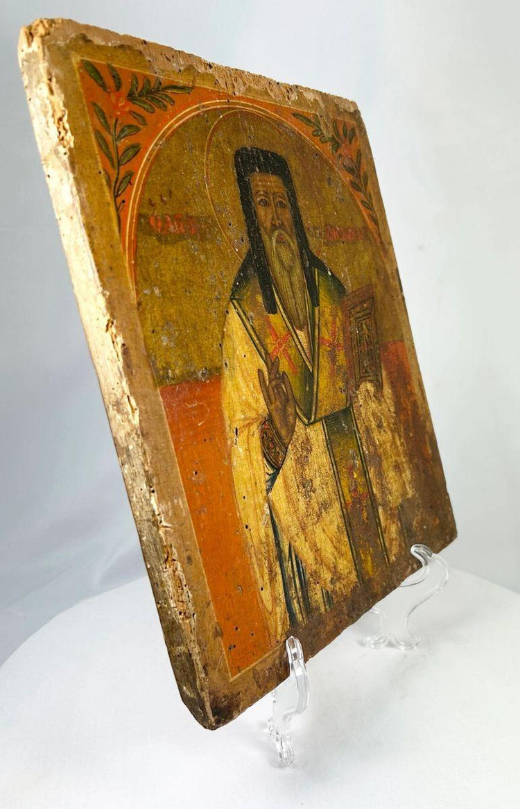Side view of an 18th-century Russian Orthodox icon of a saint holding a Gospel book, hand-painted on an aged wooden panel.
