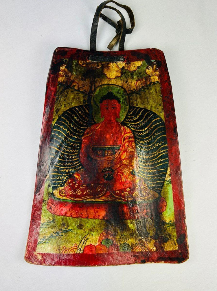 Close-up detail of hand-painted Buddhist iconography on a carved Tibetan bone plaque amulet