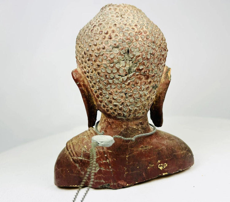 Close-up detailing the headdress, gilded remnants, and traditional Southeast Asian carving style.