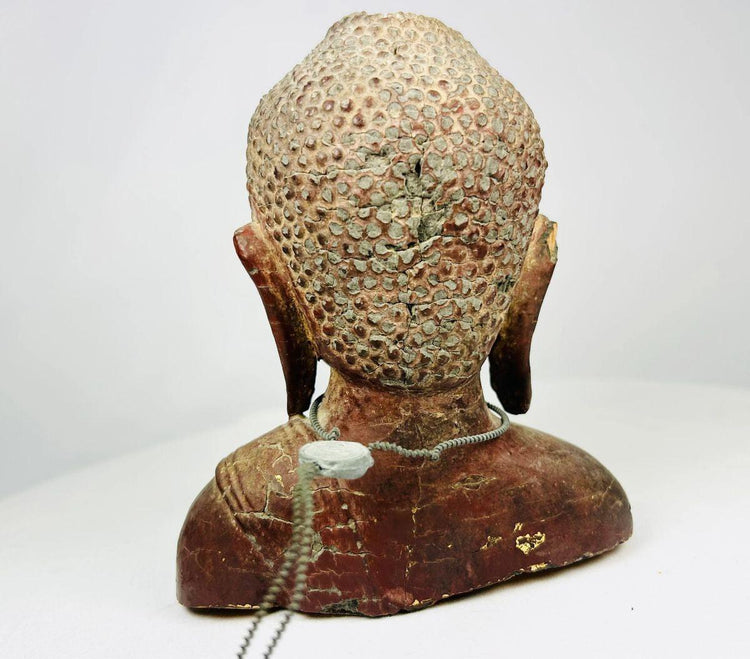 Close-up detailing the headdress, gilded remnants, and traditional Southeast Asian carving style.