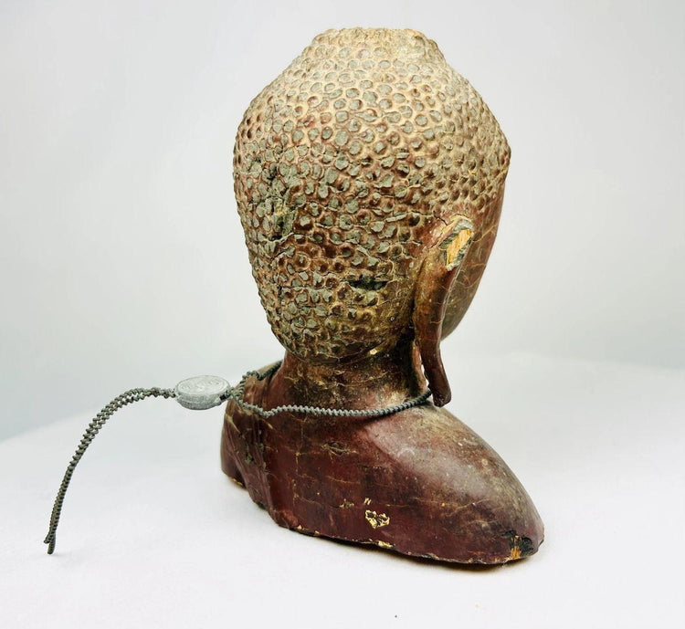 Rear view of carved wooden Buddha bust displaying patina and aged lacquer finish.