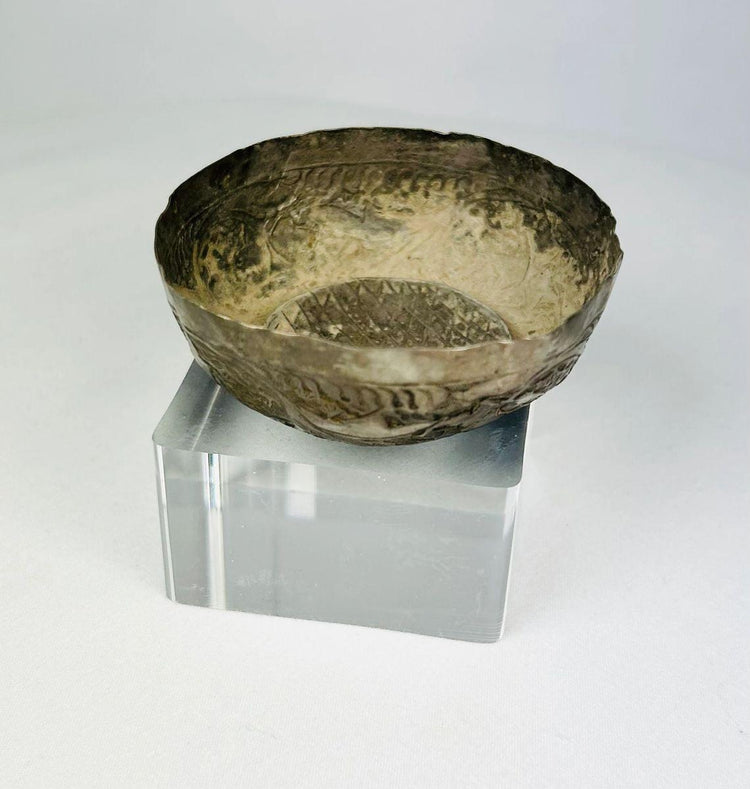 Top-angled view of a Seljuk Persian silver unguent bowl from the 12th–13th century CE, showing engraved floral and geometric interior patterns with aged patina and subtle wear from centuries of preservation.