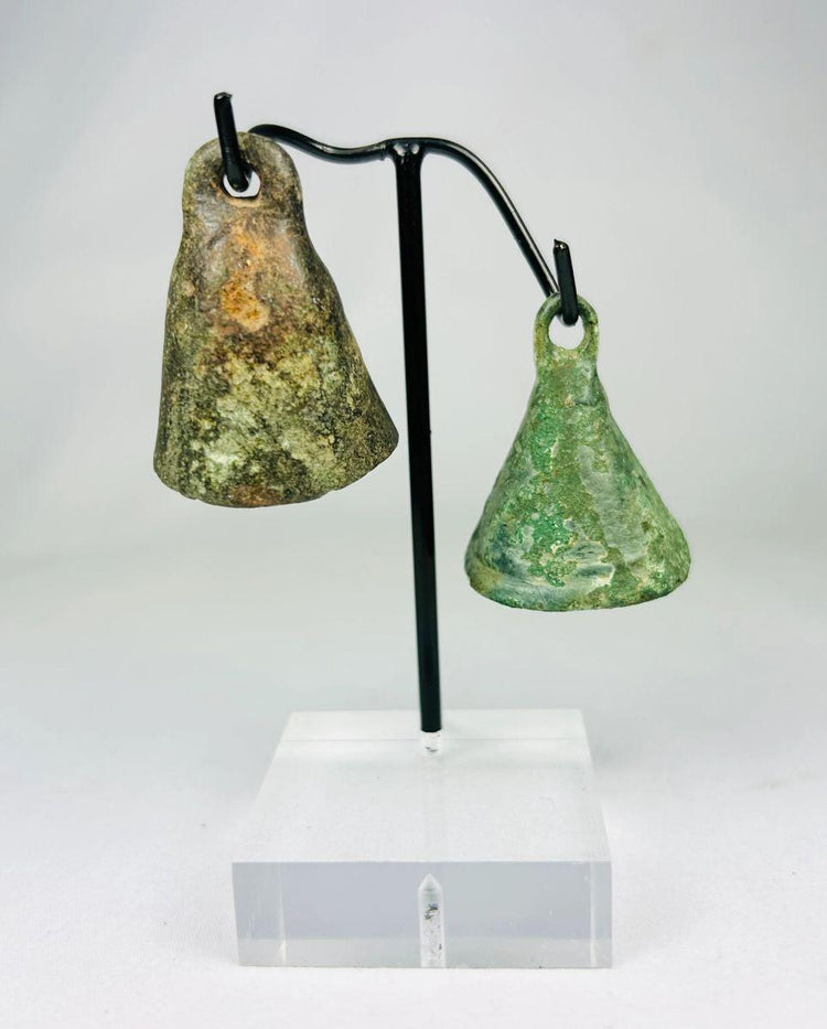 Pair of ancient Roman bronze bells mounted on a museum display stand, circa 1st–4th century CE
