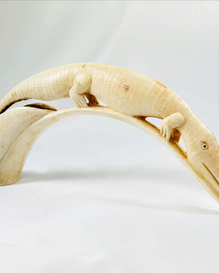 Side view of a carved African hippopotamus tooth featuring a crocodile design, early 20th-century tribal ivory artwork displayed on a white background.