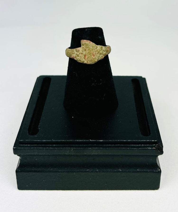 Museum-style photograph of an ancient bronze ring with natural green and brown patina