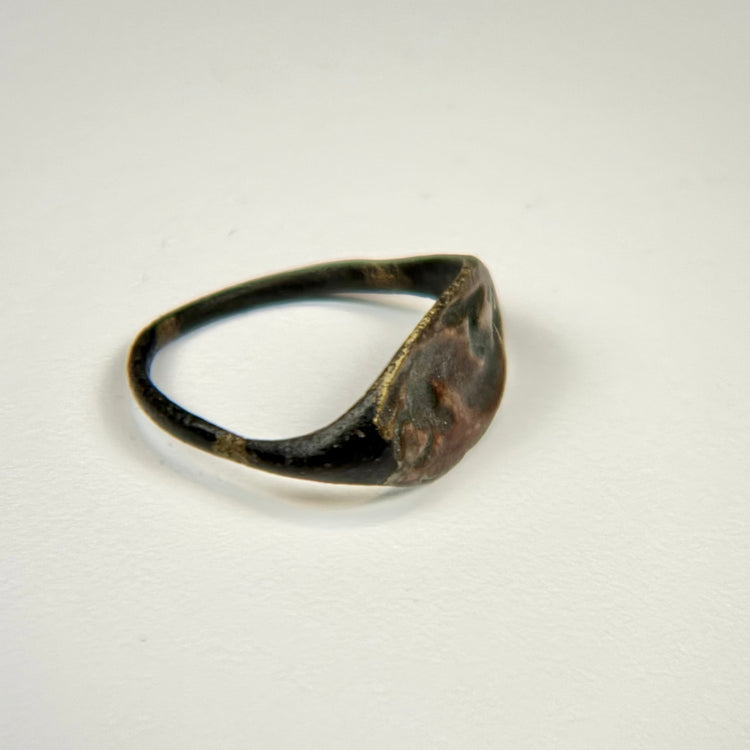 Ancient Near Eastern bronze ring showing a horned animal motif and age-related surface abrasions