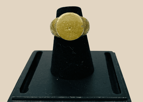 Ancient bronze ring with geometric scrollwork on a clear display stand
