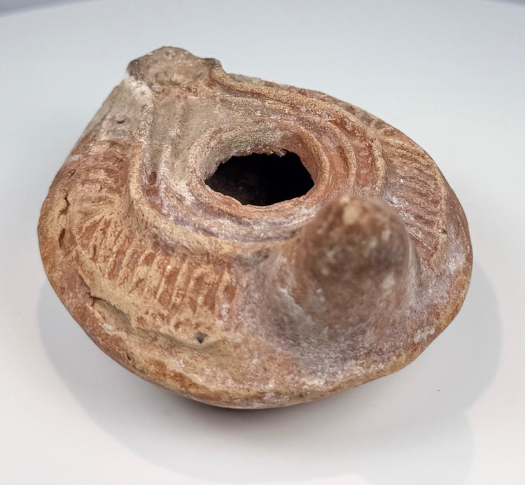 Ancient Mediterranean terracotta lamp with oval body, extended nozzle, and rear handle