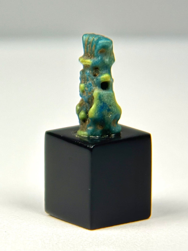 Side profile of Ancient Egyptian Bes faience figure with suspension hole through torso