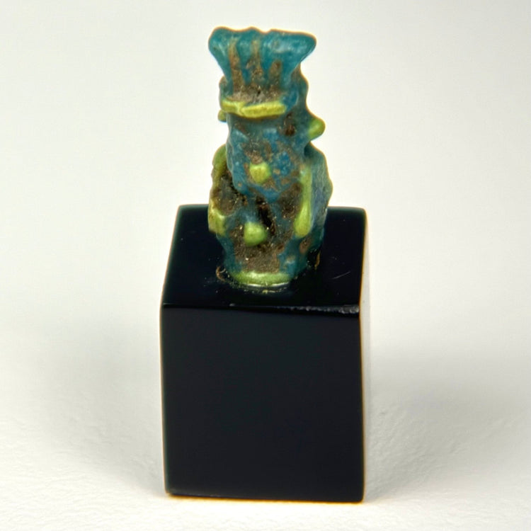 Rear view of Ancient Egyptian Bes faience amulet showing surface wear and glaze texture