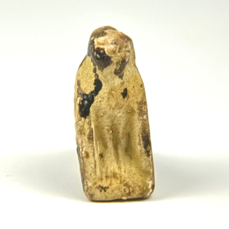 Ancient Egyptian protective falcon amulet showing a raised head, folded wings, and centuries-old mineral surface deposits.