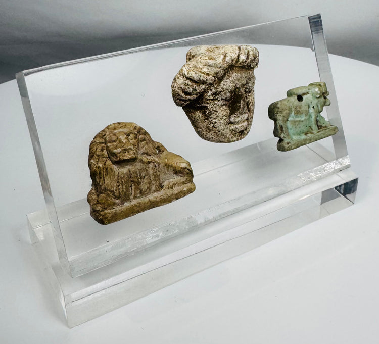 Custom-mounted display containing Egyptian, Greek, and Roman period antiquities with age-related patina and wear.
