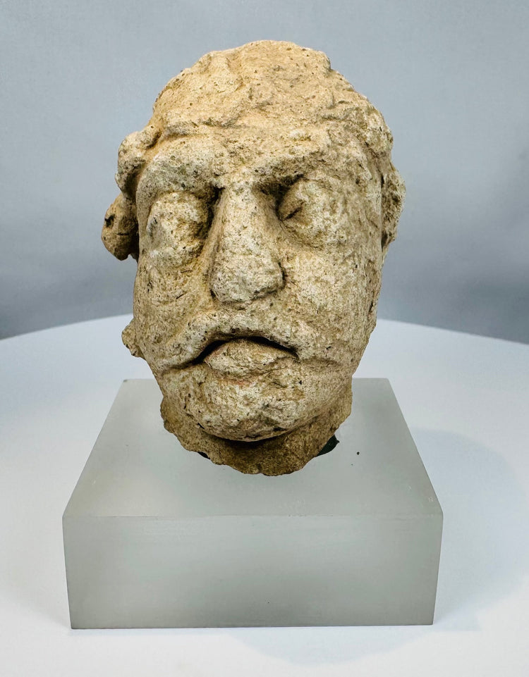 Carved limestone Bodhisattva head from ancient Gandhara with weathered facial features and archaeological surface patina.