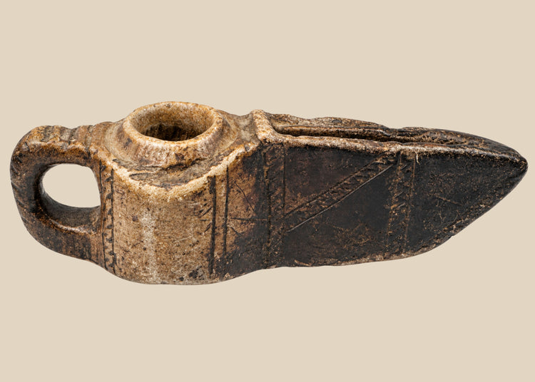 Ancient Islamic stone oil lamp from the early Islamic period (circa 7th–12th century CE). Hand-carved with geometric incised decoration, open spout for a wick, and natural patina. Reflects early Islamic artistry, domestic and ceremonial use, and cultural emphasis on geometric design and spiritual symbolism.