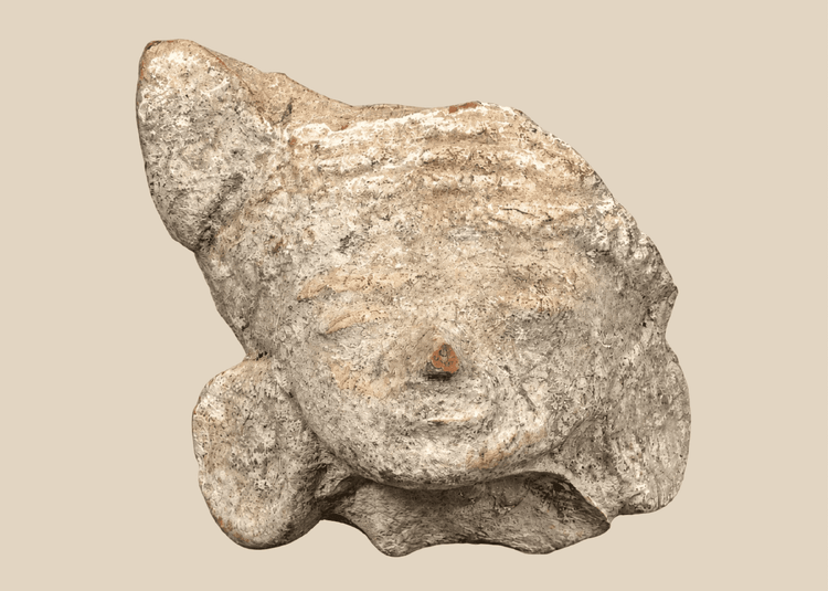 Pre-Columbian terracotta head fragment depicting a stylized human face with closed eyes and large ear ornaments.