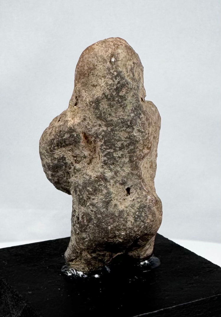 Mesoamerican carved stone human figure with compact proportions and abstract features