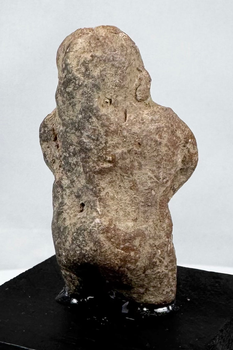 Ancient Mexican stone sculpture depicting a standing figure with arms across the abdomen