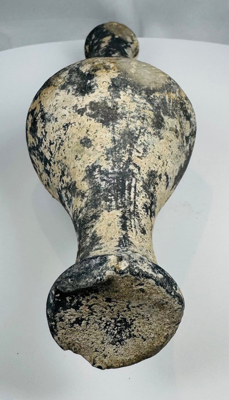 Close-up of dark burnished pottery surface with pale mineral accretions