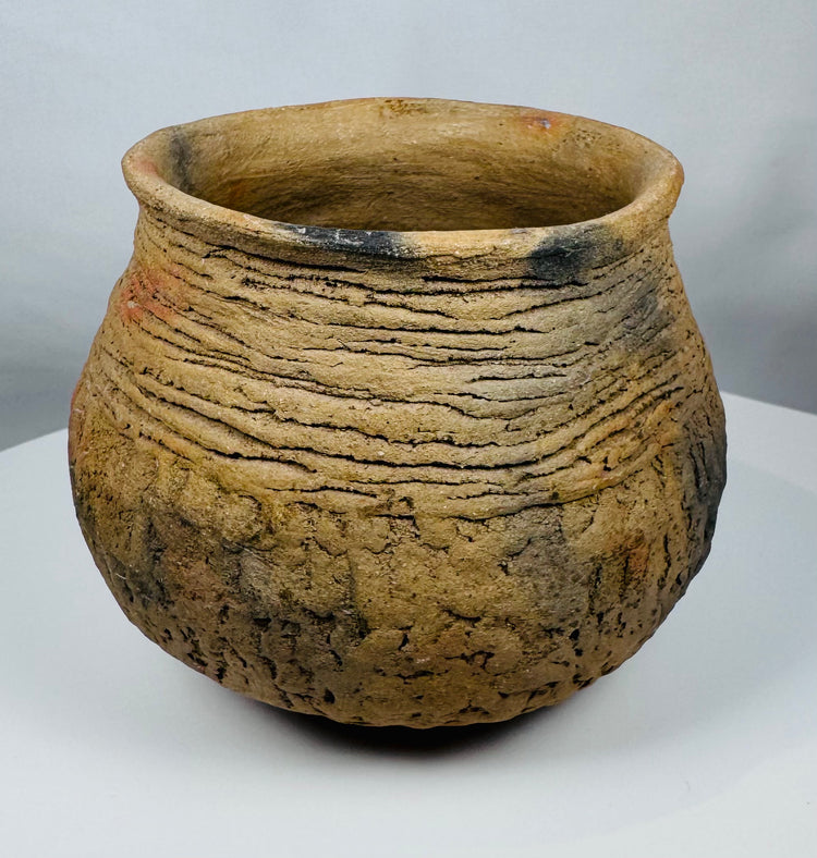 Hand-built Casas Grandes pottery jar dating to circa 1100–1450 CE, displaying traditional corrugated ceramic construction and warm buff coloration.