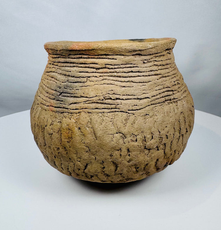 Historic Casas Grandes ceramic vessel from northern Mexico with wide mouth opening, corrugated shoulder bands, and mineral deposits.