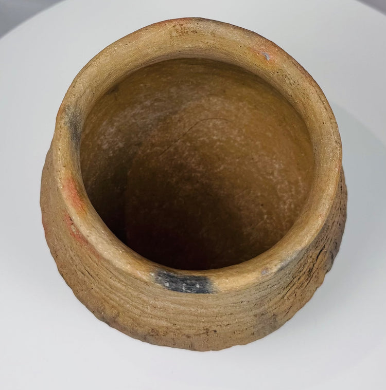 Ancient Casas Grandes storage vessel with rounded form, textured surface, and horizontal corrugated decoration around the upper body.