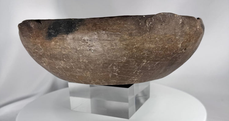 Ancient ceramic serving vessel with dark mineral deposits and thick reinforced rim