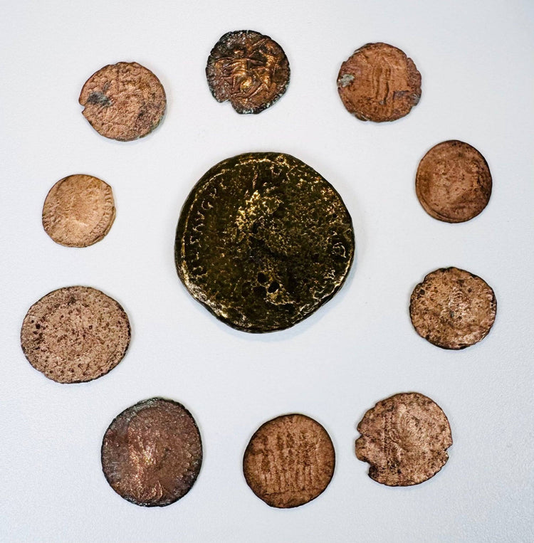Curated ring of weathered bronze coins with rust and verdigris on beige background