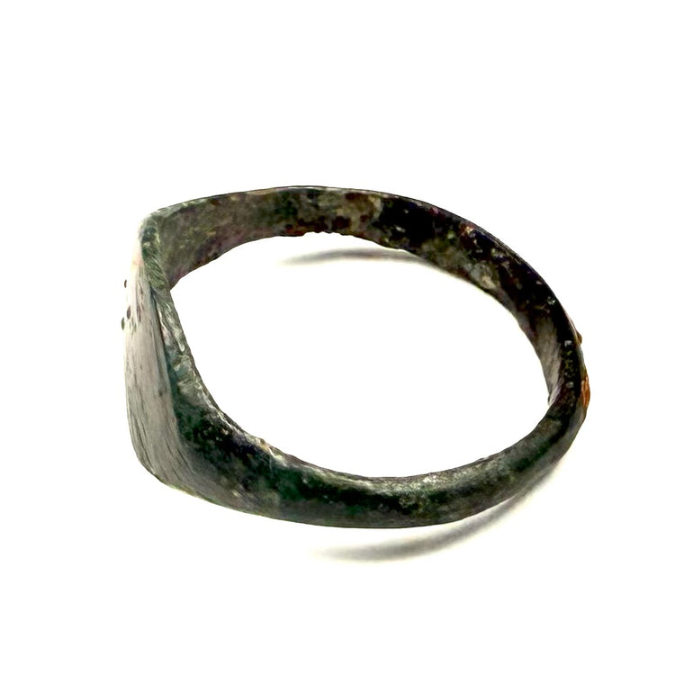 Angled view of ancient Roman bronze ring with broad undecorated oval bezel and preserved patina