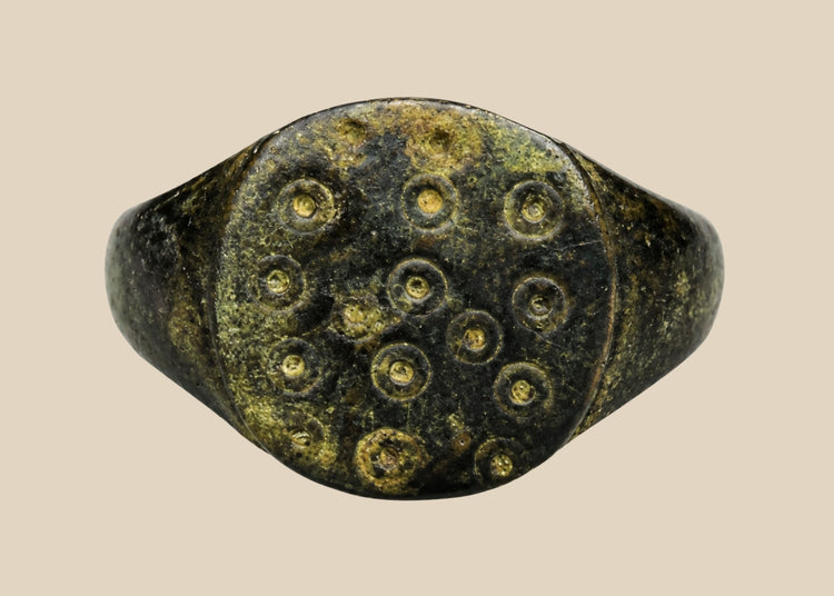 Ancient Roman bronze ring, size 7 US, featuring a flat bezel engraved with irregular “ring and dot” motifs symbolizing the sun, with authentic patina and well-preserved surface from the 1st–3rd century CE.