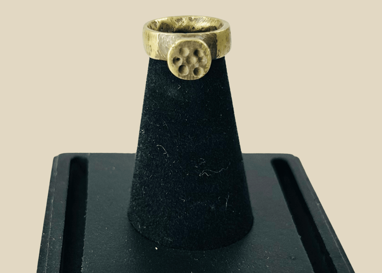 Front view of ancient Roman bronze ring showing circular rosette bezel with natural green patina.